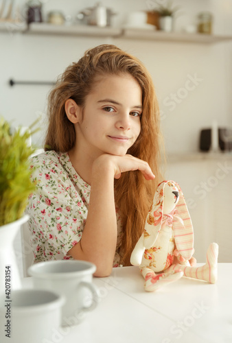  white european girl 10 years old in the kitchen at the table with Easter eggs