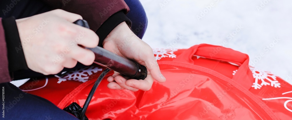 Man pumping air into tire of tube with mechanical pump on winter day. Equipment, device. Banner.	
