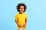 Positive African American little boy laughing in blue studio