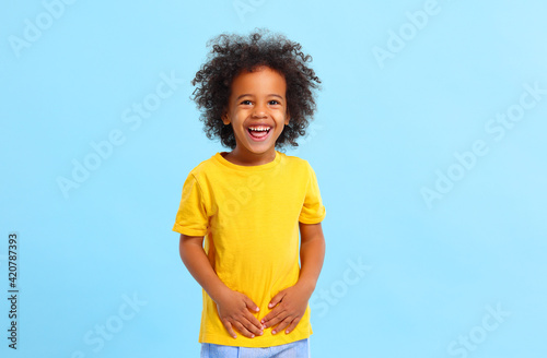 Canvas Print Positive African American little boy laughing in blue studio