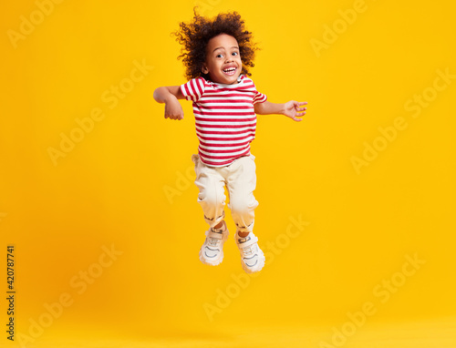 Active positive black kid jumping against blue background