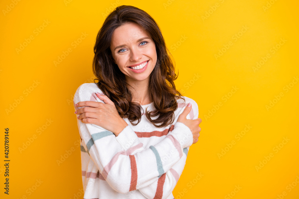 Portrait of attractive sweet tender cheerful girl hugging herself isolated over bright yellow color background Portrait of attractive sweet tender cheerful girl hugging herself isolated over bright yellow color background