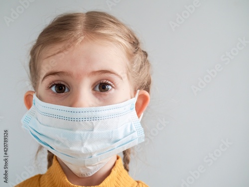 Little girl child in medical mask on grey background. Coronavirus Quarantine Concept. Wearing mask for protect Covid-19 . Copy space for text