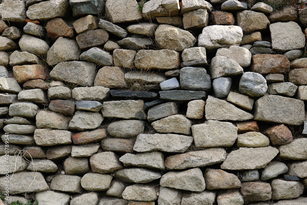 Fototapeta premium ancient stone wall background with rocks of different shapes, textures and colors