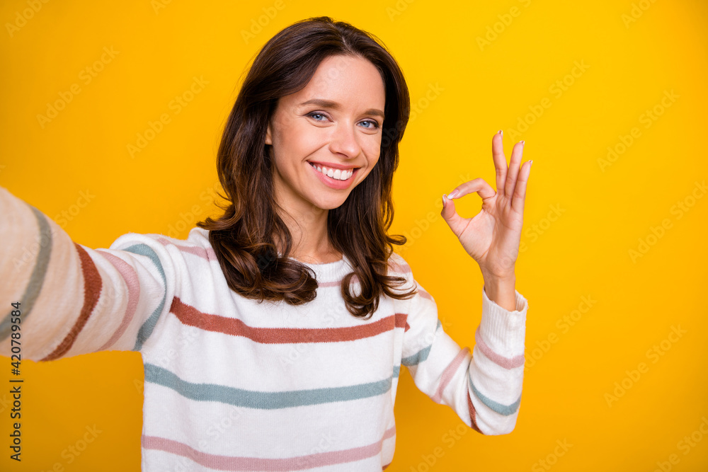 Self-portrait of attractive cheerful content girl showing ok-sign ad advert isolated over bright yellow color background Self-portrait of attractive cheerful content girl showing ok-sign ad advert isolated over bright yellow color background
