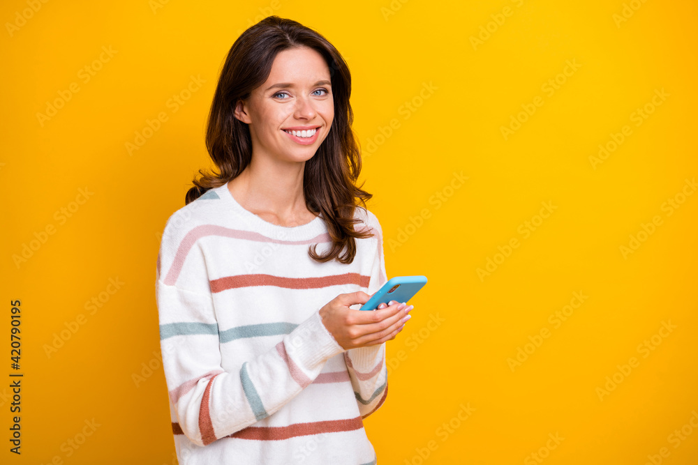 Photo of pretty cheerful person hands hold phone look camera toothy smile isolated on yellow color background Photo of pretty cheerful person hands hold phone look camera toothy smile isolated on yellow color background