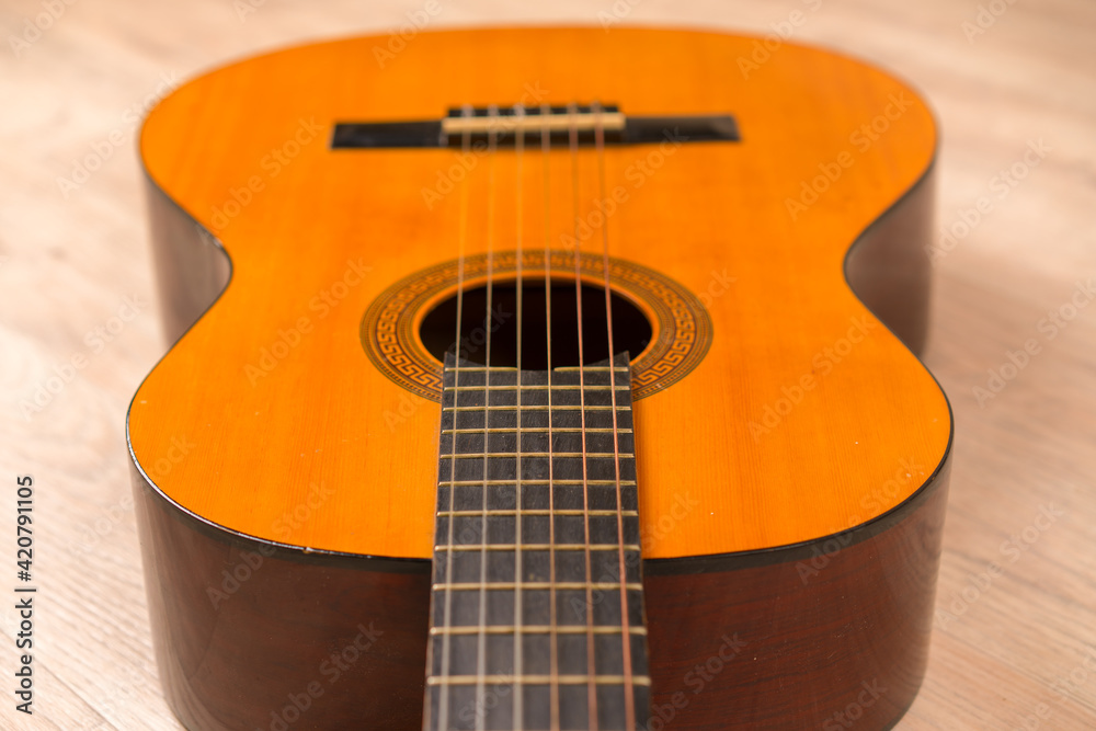 Obraz premium Classic six-string acoustic guitar on a wooden base. Selective focus.