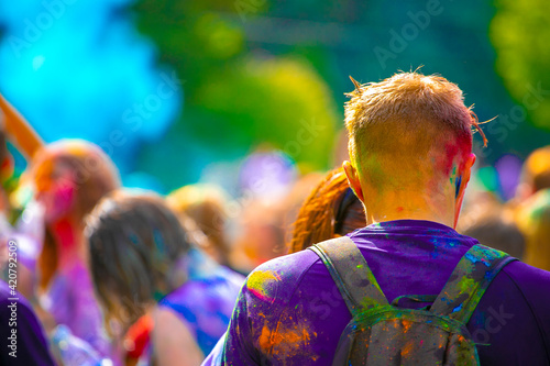 young man sprinkled with multi-colored powder at the Festival of colors.