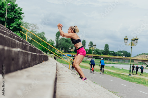 Fit healthy athlete, beautiful woman in tight sportswear jumping on stairs, warming up before jogging while looking highly motivated..