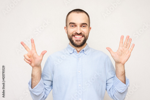 Bearded man shows fingers eight, white background, copy space