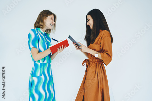 Happy women standing with notebook and tablet