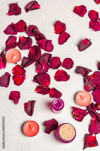 Floral and spa concept with dried roses petals, fragrant candles and soft towel