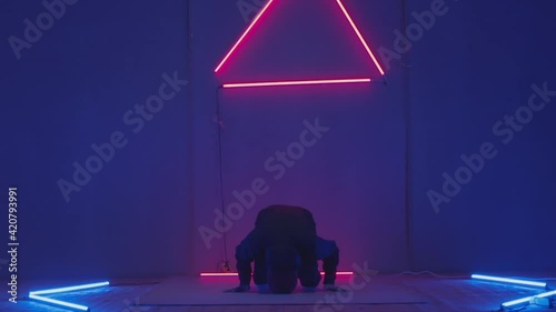 Person in windbreaker and red cap dancing to breakdance. red triangle neon background . Flickering neon background . man dancing to breakdance in night club