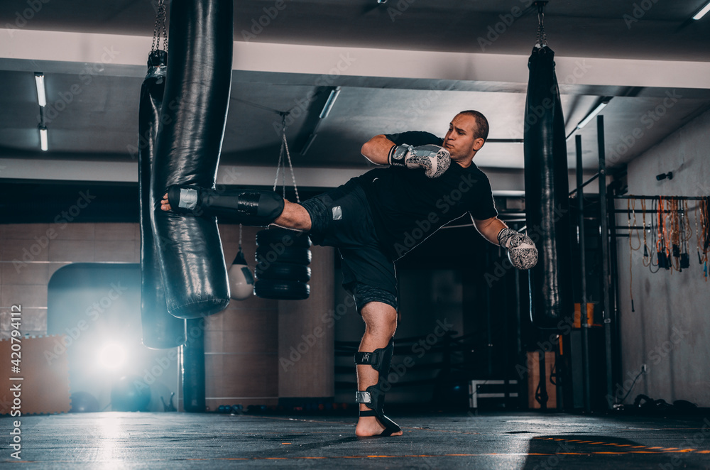 Fototapeta premium Angry muay thai fighter practicing punch on punching bag
