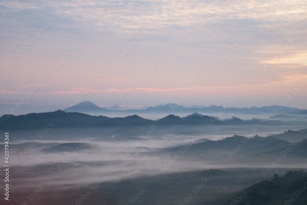 Nature scenery view of misty mountain with fog in summer morning and cloudy sky