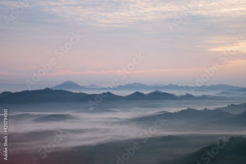 Nature scenery view of misty mountain with fog in summer morning and cloudy sky