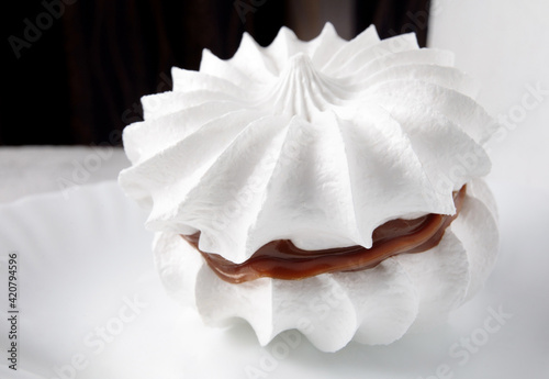 Beautiful white meringues on a white plate. White cake.