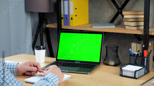 Fotografie Green screen display laptop computer concept: Businessman at home office sitting