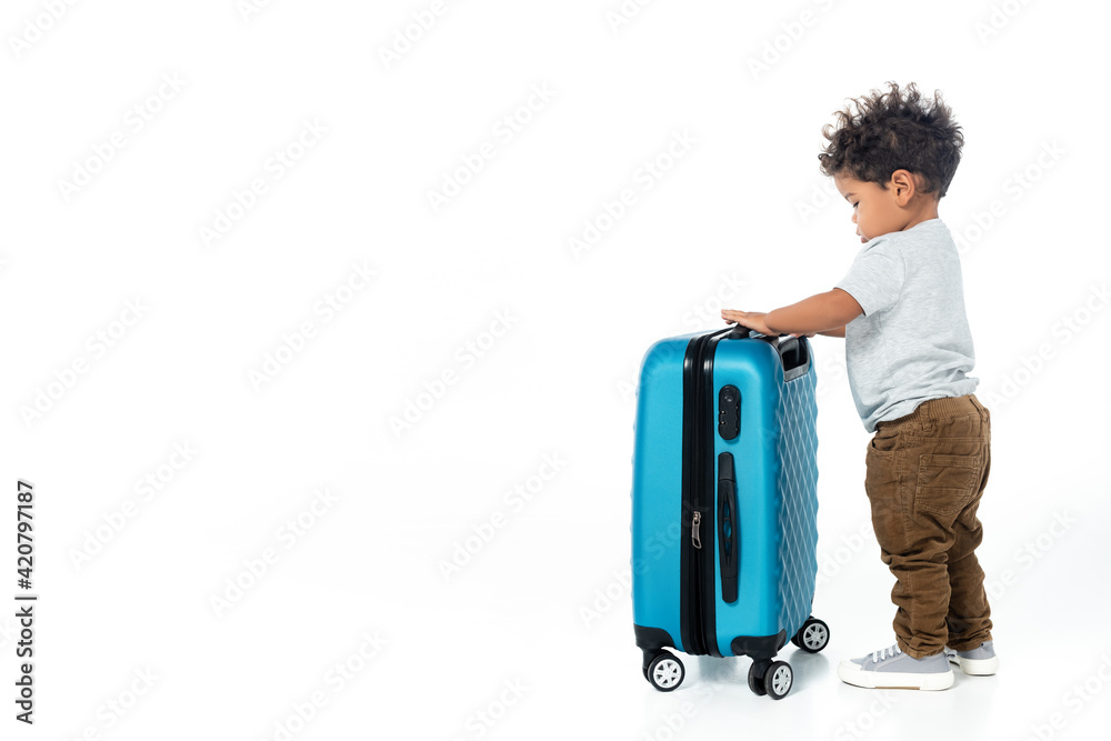 full length view of toddler african american boy standing near travel bag on white full length view of toddler african american boy standing near travel bag on white