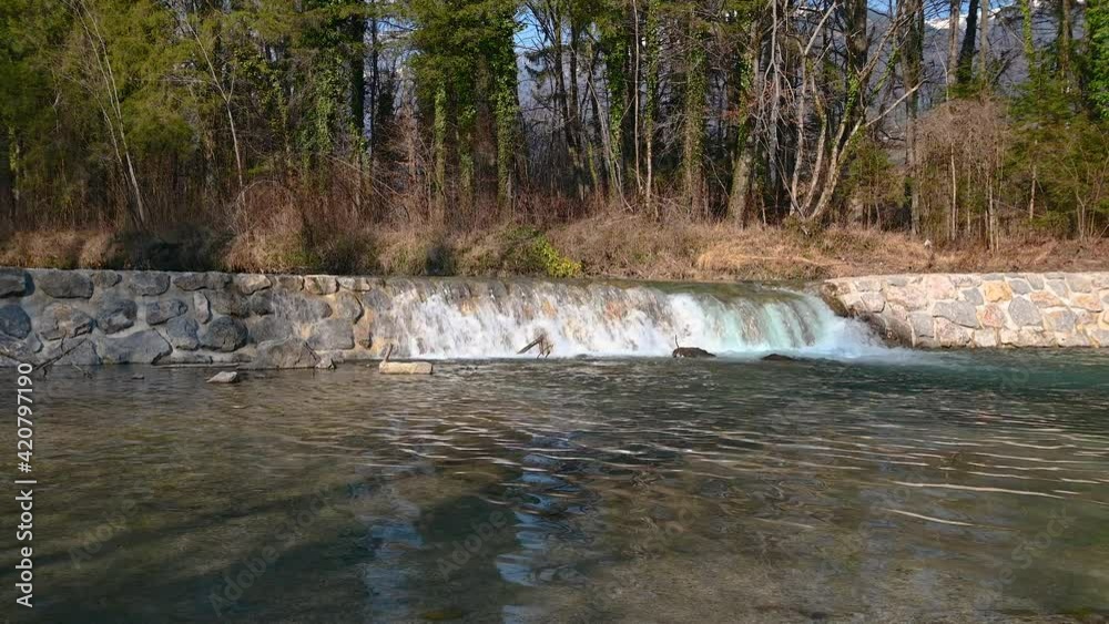 Low angle view of cam water flowing over stone manmade dam. Calm river surface. Rural retention dam. Alpine river in Slovenia. Static shot, real time Low angle view of cam water flowing over stone manmade dam. Calm river surface. Rural retention dam. Alpine river in Slovenia. Static shot, real time