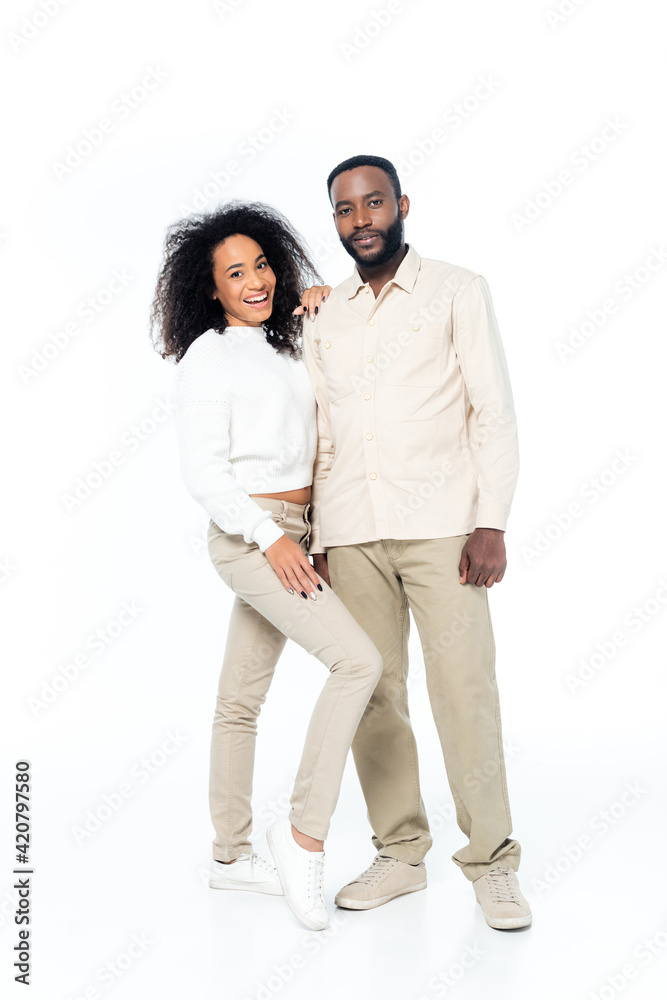 full length view of happy african american couple smiling at camera while standing on white full length view of happy african american couple smiling at camera while standing on white