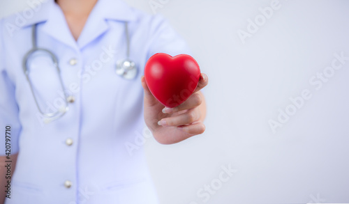   Selective focus of red heart held by female nurse's hand representing giving effort high quality service mind to patient. Professional, Specialist in uniform on white background