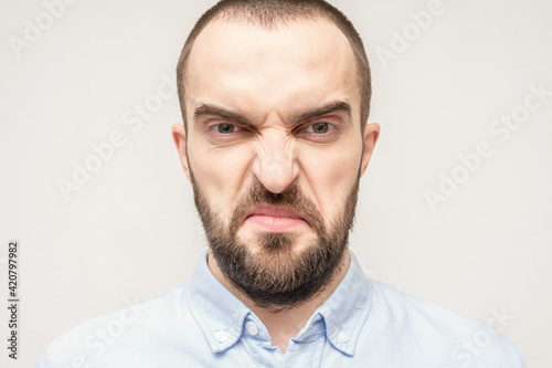 Disgust on man's face because of the fetid smell, grimace, portrait, close-up, white background