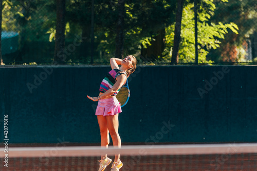 Professional equipped female tennis player serving the tennis ball on a sunny day © qunica.com