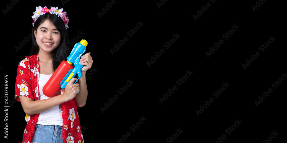 Portrait cheerful young Asian woman holding water gun Smiling and having fun playing in the water Songkran festival, Thailand. isolated on black background. Thai New Year's Day. Portrait cheerful young Asian woman holding water gun Smiling and having fun playing in the water Songkran festival, Thailand. isolated on black background. Thai New Year's Day.