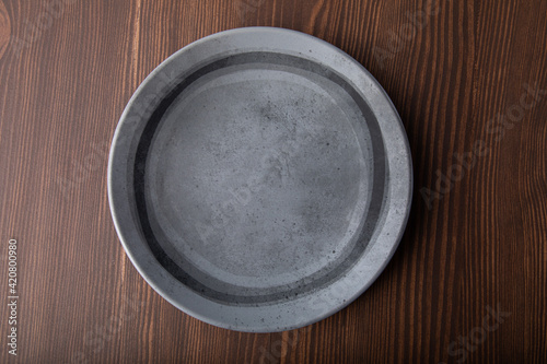 Beautiful gray handmade ceramic plate isolated on wooden background. Close-up