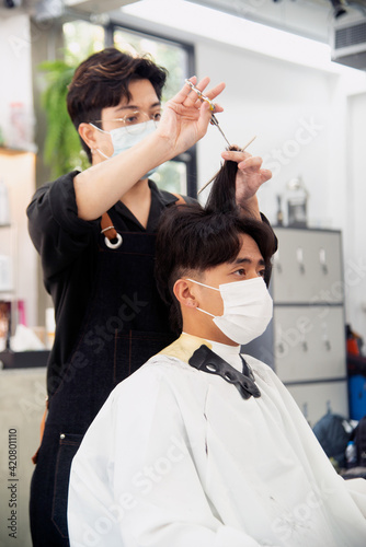 Asian male hairdresser make hairstyles for Asian male customers in modern beauty salons in Bangkok city..