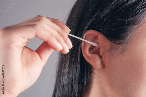 girl cleans her ears with a stick