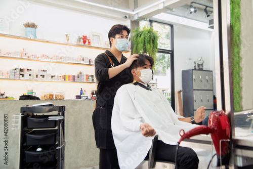 Asian male hairdresser make hairstyles for Asian male customers in modern beauty salons in Bangkok city..