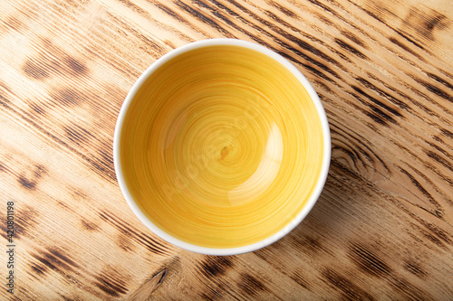 Empty white bowl with hand painted yellow inside. Isolated on wooden background