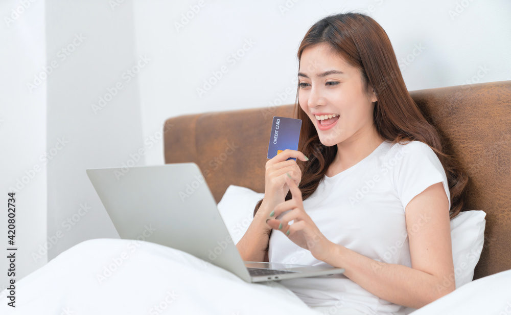 Happy asian woman doing online shopping at home, Women shopping online with credit card and laptop on the bed at home
Happy asian woman doing online shopping at home, Women shopping online with credit card and laptop on the bed at home