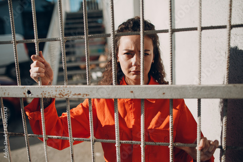 Cuadro en lienzo Young woman in orange suit behind jail bars