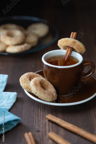Close up of a cup of tea served with mini sugar and cinnamon donuts.