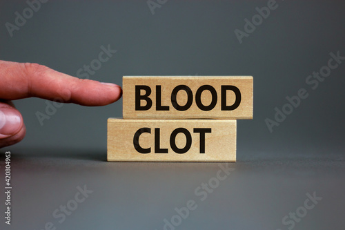 Medical and and blood clot symbol. Wooden blocks with words 'blood clot'. Beautiful grey background. Doctor hand. Medical and and blood clot concept. Copy space.