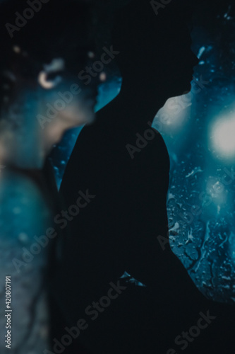 Silhouette male portrait. Nature unity. Peaceful mind. Spiritual energy. Water fantasy. Handsome man with blur lights drops splashes reflection in dark blue shadow double exposure.