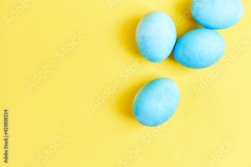 Happy Easter concept. Chicken eggs painted in blue color in the egg compartment. Preparation for holiday. Yellow background copy space