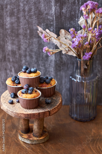 Blueberry muffin. Decoration with blueberries. Wooden background. Side view. Purple flowers