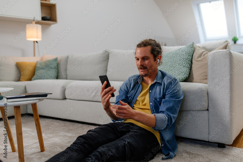 Man using a smartphone while relaxing at home. He is having video call