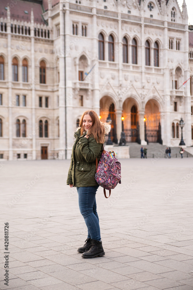 Tourist - a girl with a backpack travels across Europe. Travel to Hungary, European tour. A girl near the Hungarian parliament.