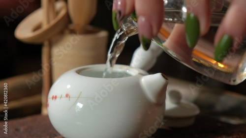 Teamaster begins the classical Chinese tea ceremony. Warms up the kettle for the ceremony. Pours water into a kettle and brews Chinese tea. Pours tea through a strainer. Authentic tea paraphernalia. photo