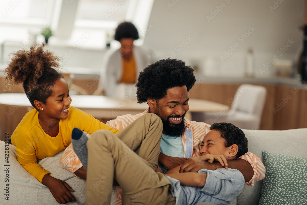 Afro children is having fun with their father in the cozy of their living room