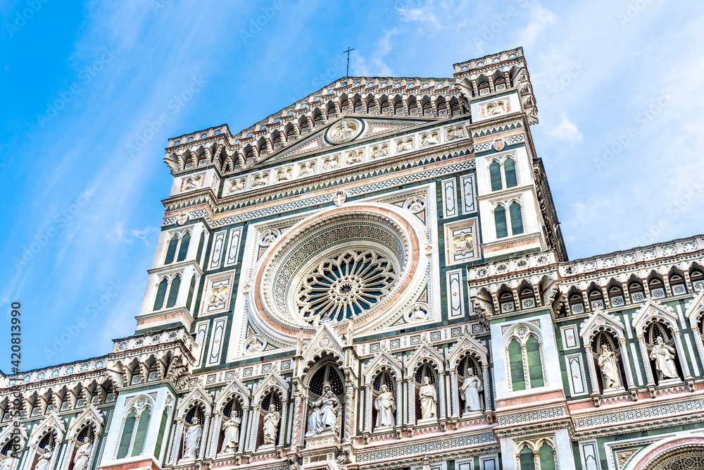 Close up on the façade of the Santa Maria del Fiore church or Florence Cathedral in neo-gothic style with white, green and red marbles, statues, niches and a rose window. 