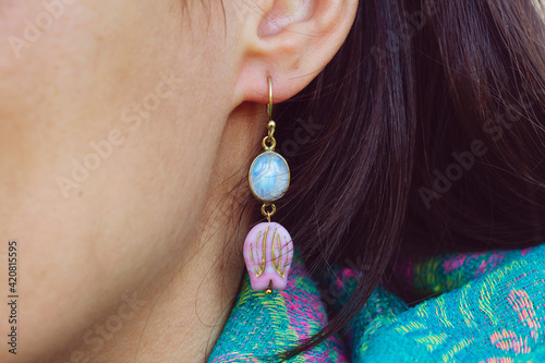 Fototapete Detail of female ear wearing moon stone mineral floral shape bead earring