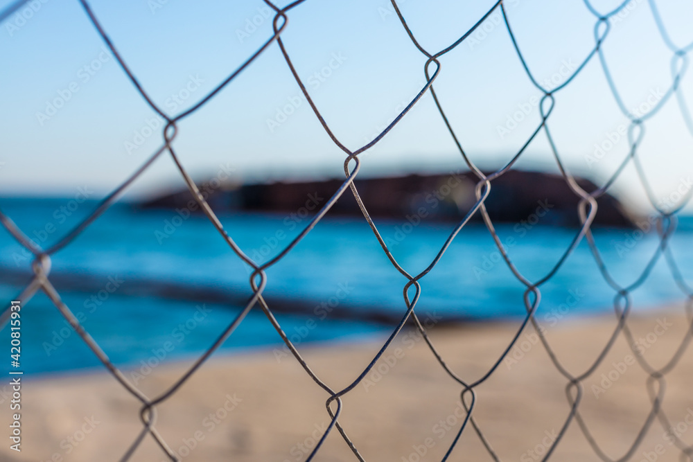 Fence mesh fence on the background of the blue sea and the sunken ship Fence mesh fence on the background of the blue sea and the sunken ship