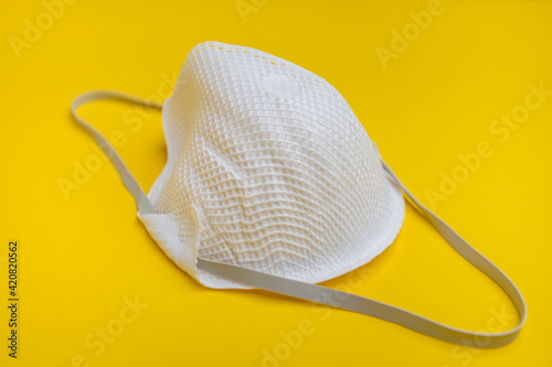 ffp2 mask with a rubber band on a yellow background.