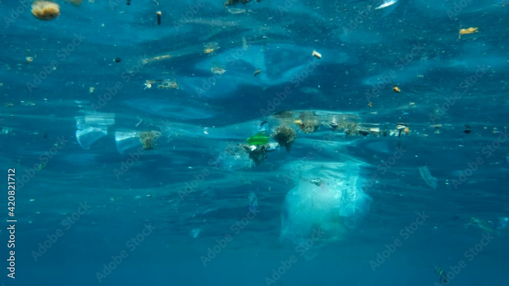Slow motion, Massive plastic and other debris slowly drifts under surface of the blue ocean in the sun lights. Plastic garbage environmental pollution problem. Plastic pollution of the Red Sea